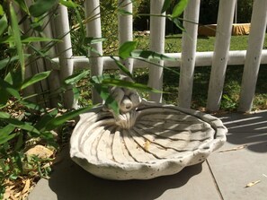 A birdbath with a decorative design, surrounded by a wooden fence and greenery. - Comfort Opale Room with Shared Pool (Saint-Cyr-sur-Loire)