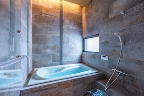 Une salle de bain moderne avec une baignoire, une douche et une fenêtre.