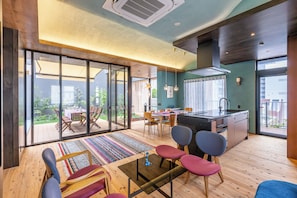 Ein modernes Interieur mit einer Küche, einem Essbereich und einer großen Schiebeglastür, die auf eine Terrasse im Freien führt.