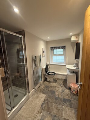 Un baño con cabina de ducha de vidrio, inodoro, bañera y ventana.