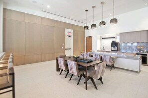 Een moderne keuken met een centraal kookeiland, een eetgedeelte met een tafel en stoelen, en een zithoek met een bank.