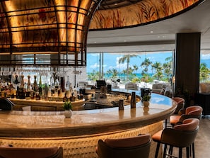 Eine Bar mit einer gebogenen Theke, Barhocker und Blick auf den Ozean.