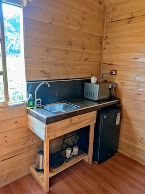 Eine kleine Küche mit Spüle, Mikrowelle und kleinem Kühlschrank.