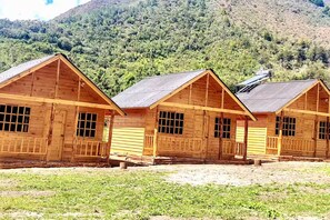 Une rangée de cabanes en bois, avec une chaîne de montagnes en arrière-plan.