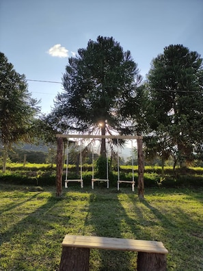 A wooden swing set in a grassy area with trees in the background.