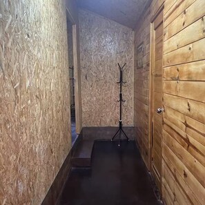 Un estrecho pasillo de madera con un perchero y una puerta.