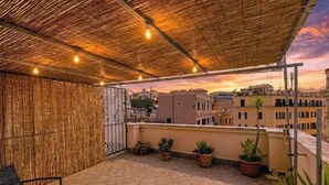 A rooftop terrace with a view of the cityscape, potted plants, and outdoor furniture. - Smart Lodging Rooftop Monti (Roma)