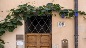 A wooden door with a metal grille, a number plaque, and a potted plant beside it. - Smart Lodging Rooftop Monti (Roma)