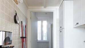 A narrow kitchen with a black countertop, a wooden cutting board, a sink, and a window leading to a bathroom. - Smart Lodging Rooftop Monti (Roma)