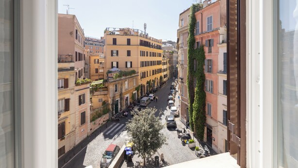 A narrow street with buildings on either side, a tree in the middle, and parked cars. - Smart Lodging Rooftop Monti (Roma)