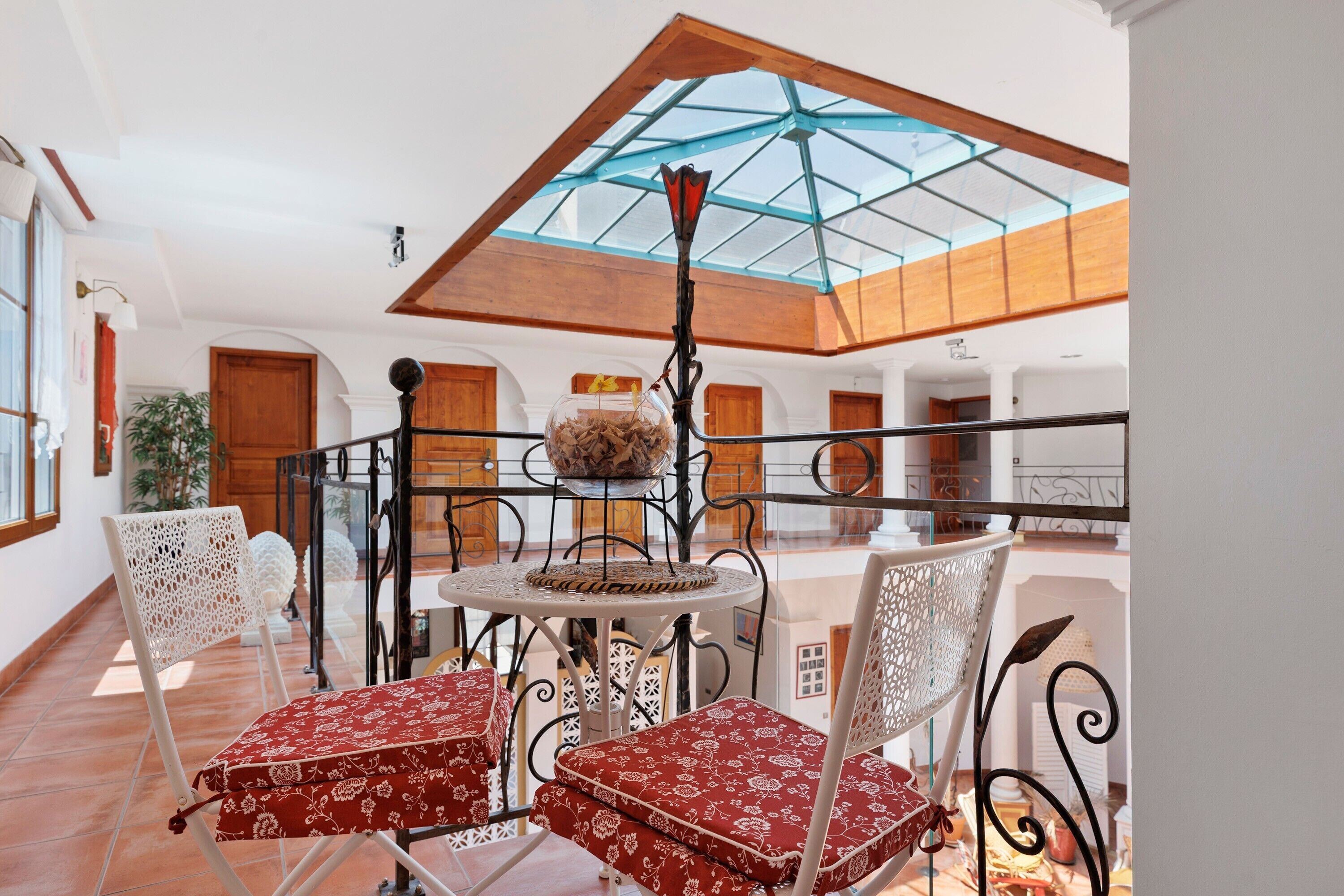 A dining area with a table and chairs, a glass ceiling, and a view of the interior.