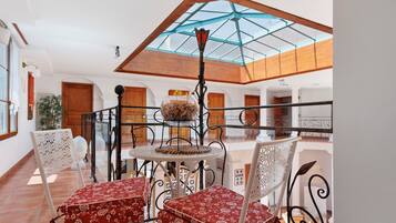 A dining area with a table and chairs, a glass ceiling, and a view of the interior.