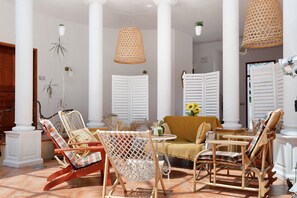 A room with wicker furniture, white shutters, and hanging plants. - Master Suite with Shared Pool (Saint-Cyr-sur-Loire)