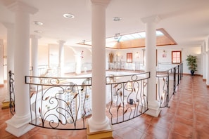 Een ruime hotel lobby met hoge plafonds, witte zuilen en een open centrale ruimte met een balustrade.