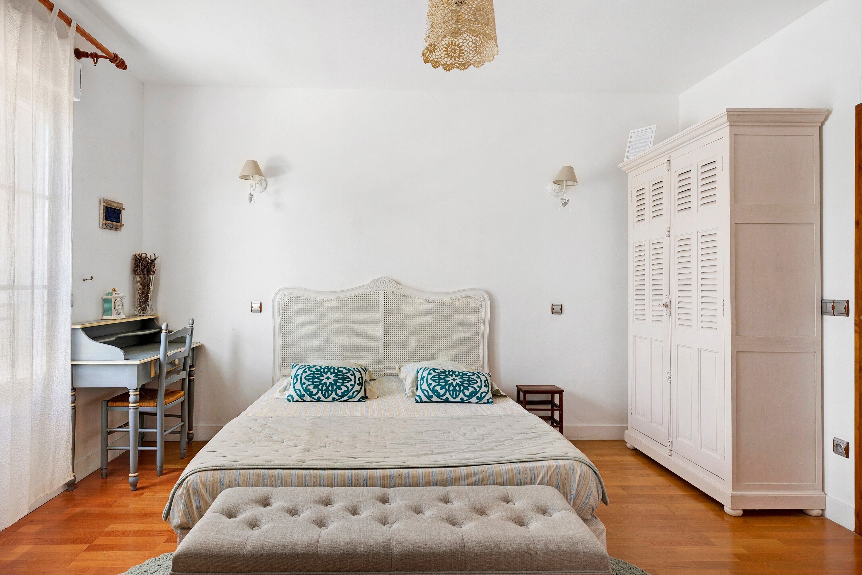 A bedroom with a bed, a desk, and a wardrobe.