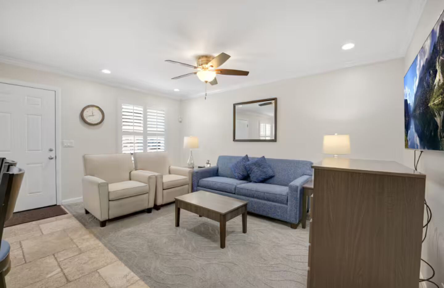 A living room with a ceiling fan, two sofas, a coffee table, and a wooden cabinet.