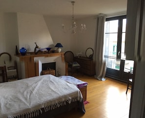 A bedroom with a bed, a fireplace, a desk, and a chair. - On the banks of the canal surrounding the town center, very bright apartment (Pamiers)