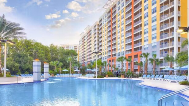 Un hotel con piscina, varios pisos y balcones.