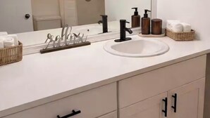 A bathroom with a white vanity, a large mirror, a sink, and a shower area. - Quiet studio w private outdoor area close to major amenities (Sunrise)