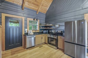 A modern kitchen with wooden cabinets, stainless steel appliances, and a black door. - Relaxing Escape, Sleeps 4, Near Dollywood, Hot Tub (Sevierville)