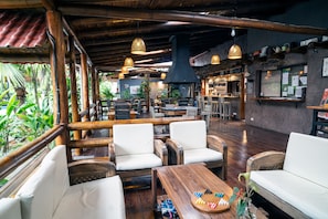Un restaurante con mobiliario de madera, luces colgantes y una zona de bar.