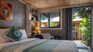 Ein Schlafzimmer mit Bett, Schreibtisch, Stuhl, Fenster und einem Balkon.