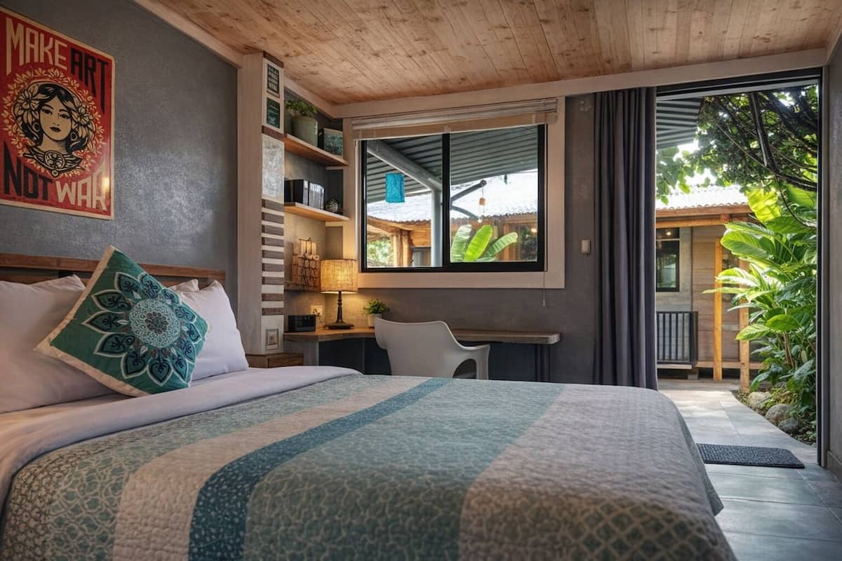 A bedroom with a bed, a desk, a chair, a window, and a balcony.