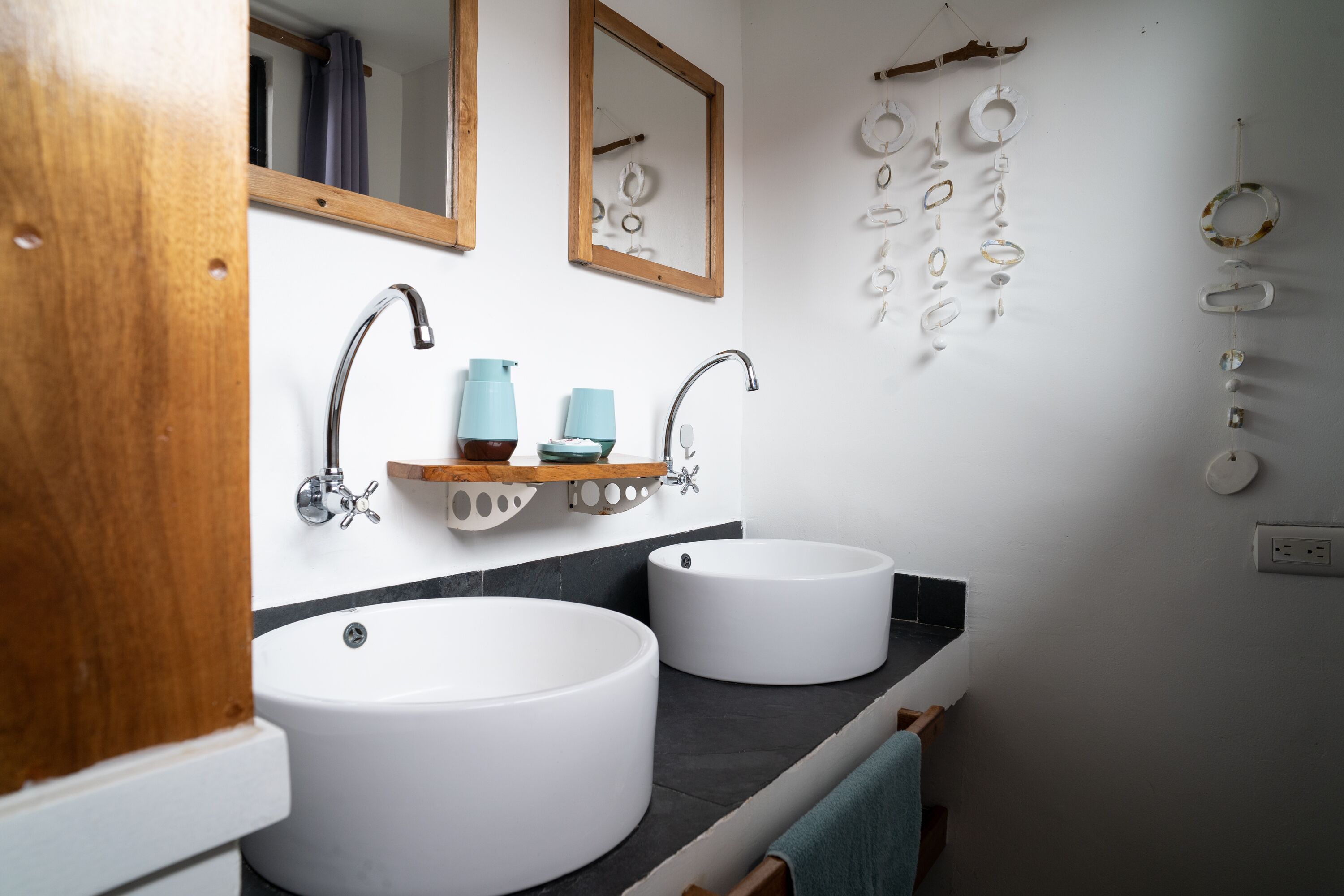 A bathroom with two sinks, a mirror, and a shelf with toiletries.