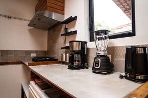 A kitchen with a stove, coffee maker, blender, and a window with a view. - La Bicok (Mindo, San Miguel de los Bancos)