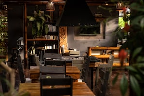 A cozy restaurant interior with wooden furniture, a bookshelf, and a hanging light fixture. - La Bicok (Mindo)