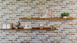En tegelvägg med två hyllor i trä där olika föremål är utställda.
