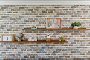 Eine Backsteinmauer mit zwei hölzernen Regalen, auf denen verschiedene Gegenstände präsentiert werden.