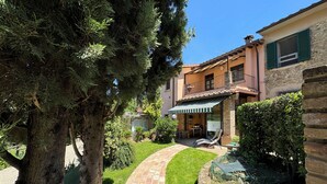 A two-story building with a brick pathway leading to a covered outdoor seating area. - Casa Greta - Flo Apartments 34 (Montespertoli)