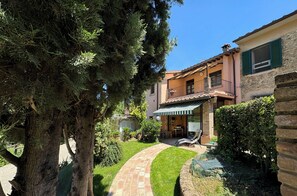 A two-story building with a brick pathway leading to a covered outdoor seating area.