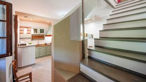 A modern kitchen with green cabinets, a central island, and a staircase with glass railings. - Casa Greta - Flo Apartments 34 (Montespertoli)