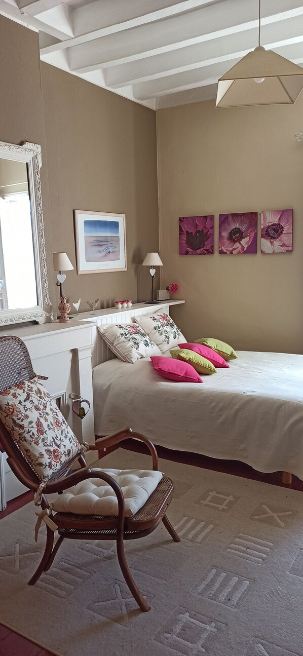 Une chambre à coucher avec un lit, une chaise, une commode et un tableau accroché au mur.