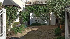 A building with a white facade, a gated entrance, and a pathway leading to a covered area.