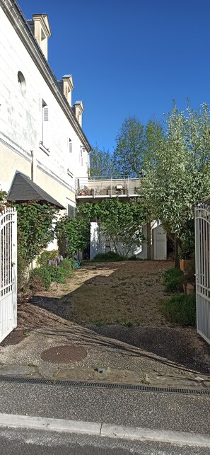 A building with a white facade, a gated entrance, and a pathway leading to a covered area.