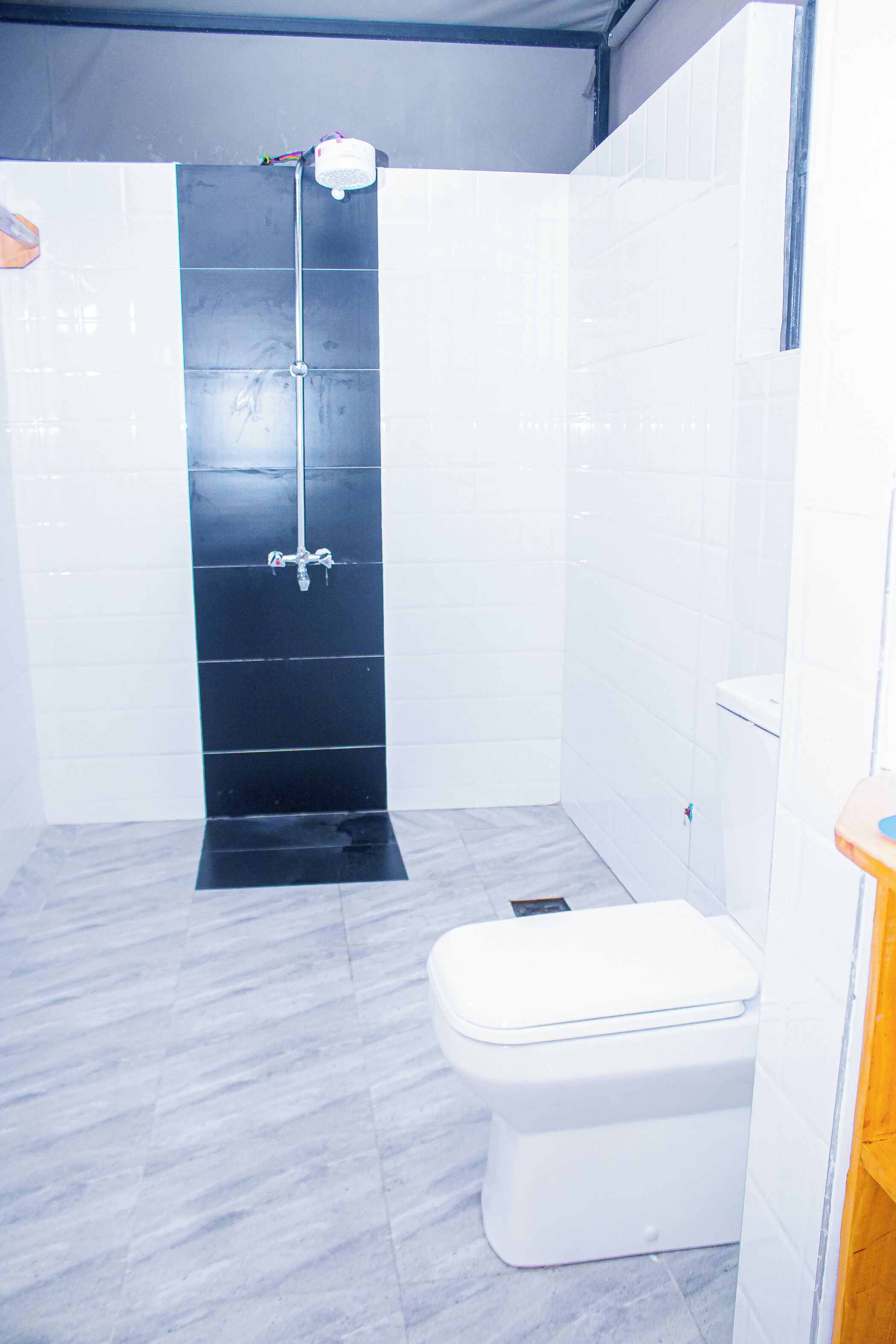 A bathroom with a shower, toilet, and tiled walls.