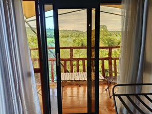 A wooden deck with a metal railing, a covered area with a view of a green landscape. - Mimosa Park and Island Camp (Sagana)