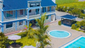 Un edificio con un letrero que dice 'Mimosa Park', rodeado de follaje y una piscina.