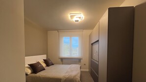 A bedroom with a bed, a window, a radiator, and a wardrobe. - Cozy suite with contemporary design and comfort for 4 guests Suite Aura (Vernazzano Basso)