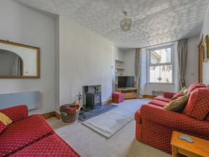 A living room with a sofa, a television, a fireplace, and a window with curtains.