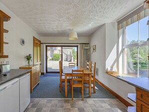Una cocina moderna con comedor, ventanas amplias y vistas al exterior.