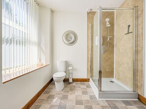 Un baño con inodoro, ducha y ventana.