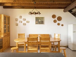 Ein Holzespeisesaal mit Stühlen, ein Holzschrank, ein Kühlschrank und Wanddekorationen, darunter gerahmte Fotos und Teller.