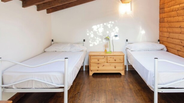 A room with two single beds, wooden flooring, a wooden ceiling, and a wall-mounted light fixture. - Beautiful private villa for 4 guests with WIFI, TV, terrace, pets allowed and panoramic view (Montemezzo)