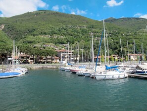 Ein Yachthafen mit vertäuten Booten, eine Hügelside mit Gebäuden und ein klarer Himmel.