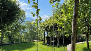 A wooden swing set in a grassy area with trees and a fence in the background. - Beautiful private villa for 4 guests with WIFI, TV, terrace, pets allowed and panoramic view (Montemezzo)