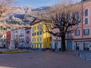 Una plaza adoquinada con edificios coloridos, una estatua y una montaña al fondo.